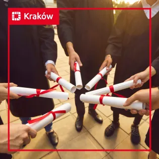 Grupa absolwentów trzymających dyplomy w rękach.