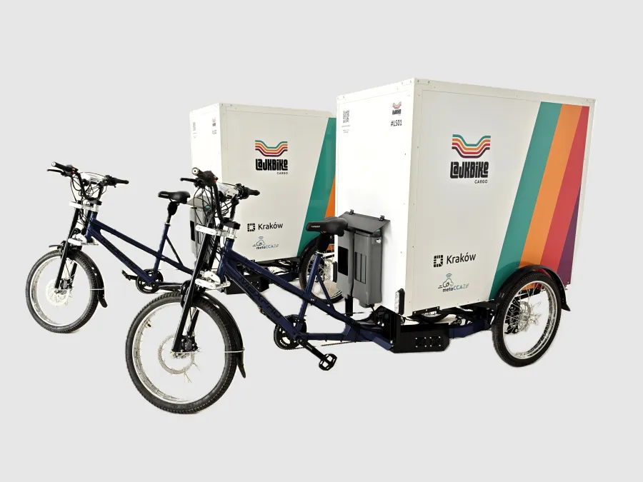 Dwa rowery cargo z przyczepami, z kolorowym logo i napisem Kraków.