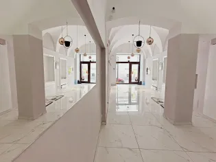 Nowoczesne wnętrze z białymi ścianami, dużymi oknami i lustrami.