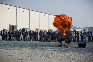 Eksplozja z ognistym wybuchem podczas demonstracji, z widownią w tle.
