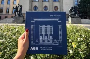 Budynki Akademii Górniczo-Hutniczej z książką o architekturze w ręku.