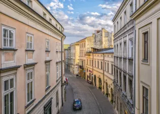 Urokliwa uliczka z kamienicami, oświetlona słońcem, prowadząca do dalszej części miasta.