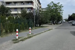 Nowoczesny budynek mieszkalny przy ulicy, z zielenią i chodnikiem.