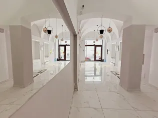 Nowoczesne wnętrze z białymi ścianami, dużymi oknami i lustrami.