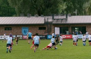 Młodzi zawodnicy rugby grają na boisku, walcząc o piłkę.
