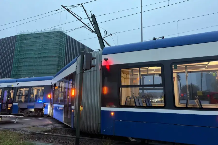 Tramwaj zatrzymany na przystanku, w tle budynek w remoncie.