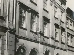 Zabytkowa kamienica z uszkodzonymi oknami i charakterystyczną architekturą.