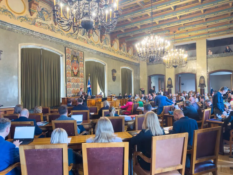 Sala obrad z uczestnikami, mównicą i dekoracyjnym sufitem.