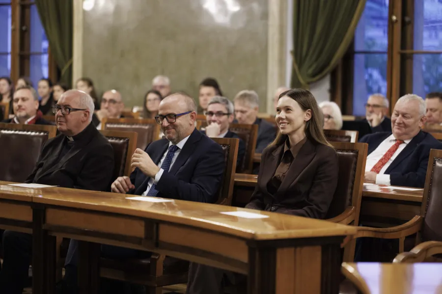 Na sali Obrad w budynku Urzędu Miasta Krakowa w ławach zasiadają kobiety i mężczyźni 