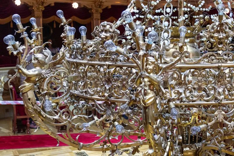 Luksusowy żyrandol z rzeźbionymi aniołkami i licznymi żarówkami.