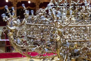 Luksusowy żyrandol z rzeźbionymi aniołkami i licznymi żarówkami.