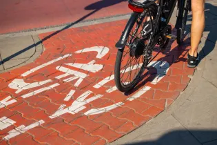 Ścieżka rowerowa z czerwonymi kafelkami i białym symbolem roweru.