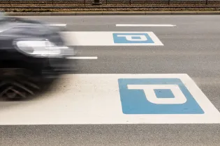 Znak parkingowy na drodze z przejeżdżającym samochodem.