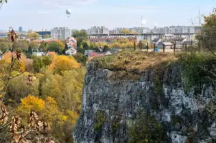 Widok na miasto z klifu, w tle balon na uwięzi i kolorowe drzewa jesienne.