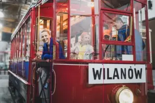 Tramwaj z napisem Wilanów w zajezdni, osoby w środku uśmiechają się.