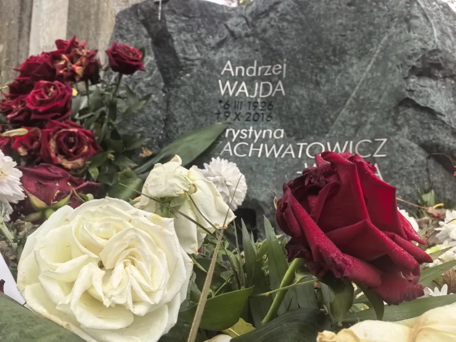 Grób Andrzeja Wajdy z kwiatami w różnych kolorach.