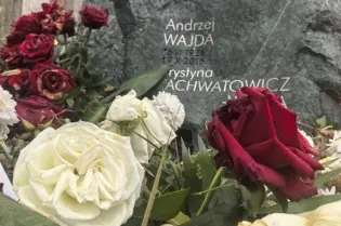 Grób Andrzeja Wajdy z kwiatami w różnych kolorach.