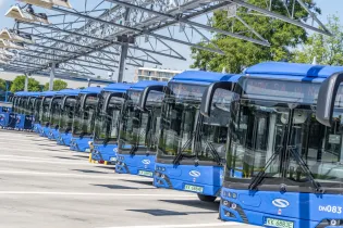 Zestaw niebieskich autobusów stojących w zajezdni.
